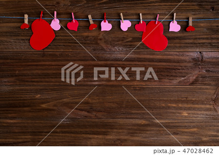 clothespins with red hearts on a ribbon as a border on a brown wooden background with space for text clothespins with red hearts on a ribbon as a border on a brown wooden background with space for text 47028462