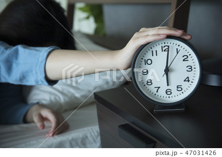 目覚まし時計を止める女性 47031426
