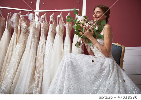 Happy bride in wedding dress enjoying flowers 47038530
