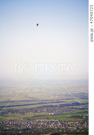 Hot air balloon above the green field and villages 47040725