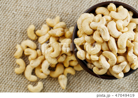 Cashew nuts in a wooden bowl on a burlap cloth  47049419