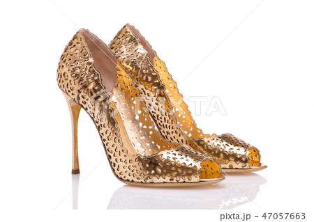 A pair of gold shoes on a white heel.  47057663