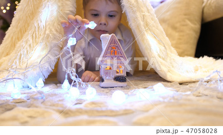 The child plays in the children's room in a tent with a Christmas light. Happy childhood 47058028