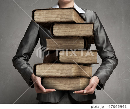 Woman carrying stack of books 47066941