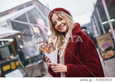 Close-up of young blonde woman eatting churros 47067835