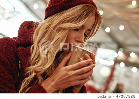 Close-up of woman drinking mulled wine at the street food market. Close-up of woman drinking mulled wine at the street food market. 47067939