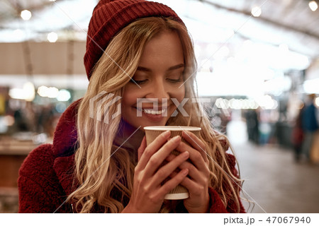 Close-up of woman drinking mulled wine at the street food market. Close-up of woman drinking mulled wine at the street food market. 47067940