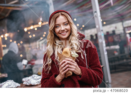 Young blonde woman eating out sandwich at sandwich bar Young blonde woman eating out sandwich at sandwich bar 47068020