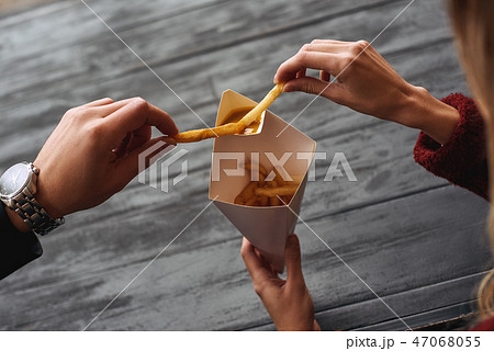 Close-up of young couple are eating french fries at the street food market. Close-up of young couple are eating french fries at the street food market. 47068055