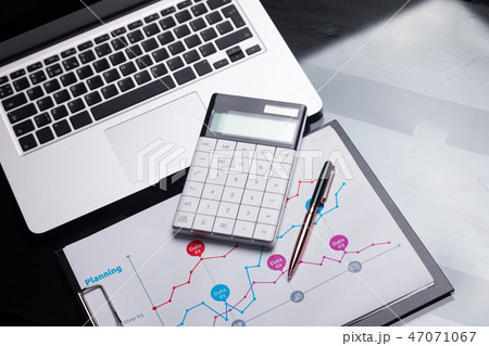 Modern calculator is on a laptop and on a sheet with a graph Modern calculator is on a laptop and on a sheet with a graph 47071067