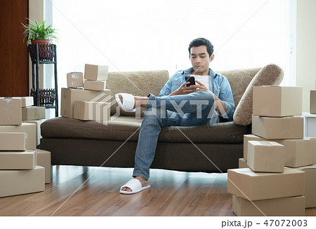 Handsome man sitting sofa used smartphone with box 47072003