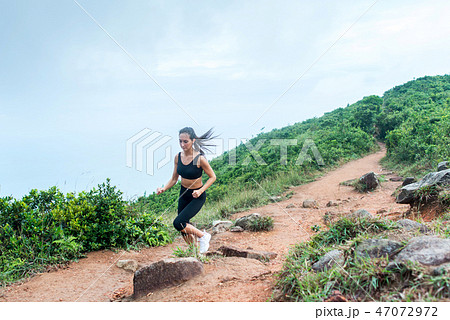 Sporty young woman in black sportswear trail running on mountain nature path. Fit girl jogging 47072972