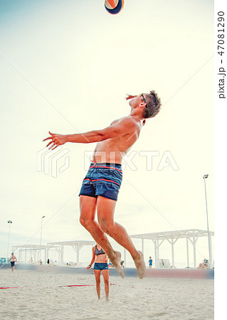 Volleyball beach player is a male athlete volleyball player getting ready to serve the ball on the 47081290