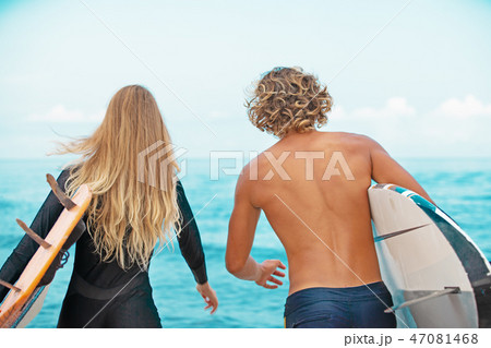 Surfers at the beach- Smiling couple of surfers walking on the beach and having fun in summer 47081468