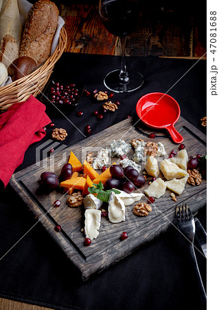 Cheese plate served with grapes, honey and nuts on a wooden background. Various types of cheese 47081688
