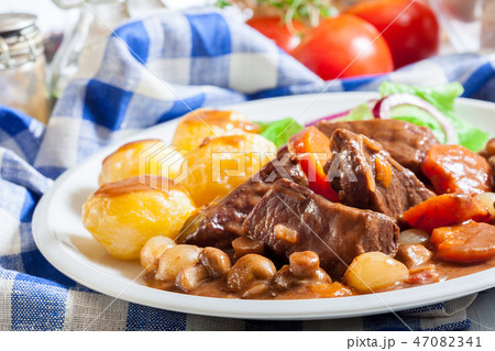 Beef Bourguignon stew served with baked potatoes Beef Bourguignon stew served with baked potatoes 47082341