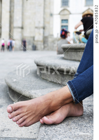 man resting barefoot on the street 47085832