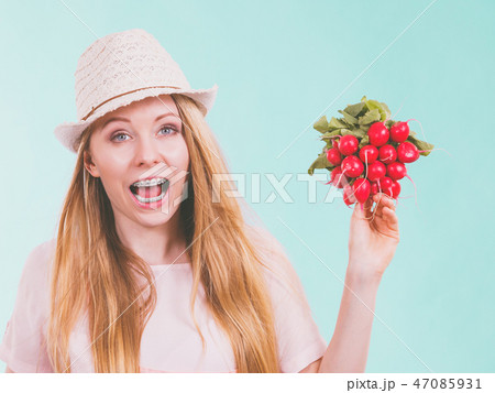 Happy woman holding radish 47085931
