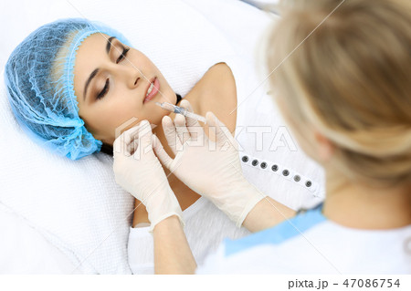 Professional cosmetologist making injection in face, lips. Young woman gets syringe with filler for Professional cosmetologist making injection in face, lips. Young woman gets syringe with filler for 47086754