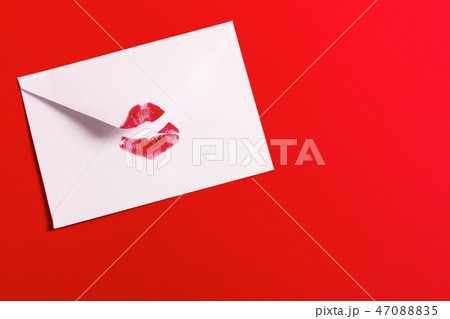 Red lipstick kiss on white envelope on red background. 47088835