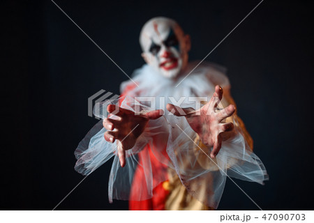 Bloody clown reaching for victim with his hands Bloody clown reaching for victim with his hands 47090703