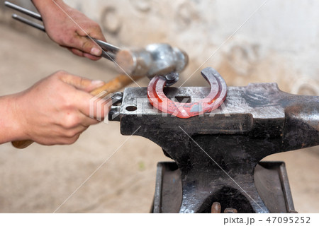 Blacksmith working on the anvil, making a horseshoe. Blacksmith working on the anvil, making a horseshoe. 47095252