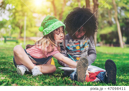 School boy and girl reading book together in park. 47098411