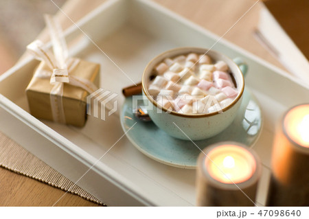 hot chocolate, christmas gift and candles on table 47098640