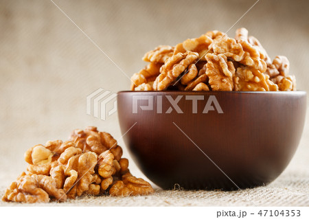 Peeled walnuts in a wooden, dark brown cup on  47104353