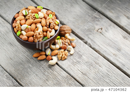 Wooden bowl with mixed nuts on a wooden gray Wooden bowl with mixed nuts on a wooden gray 47104362
