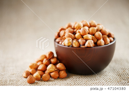 Peeled hazelnuts in a wooden, dark brown cup Peeled hazelnuts in a wooden, dark brown cup 47104380