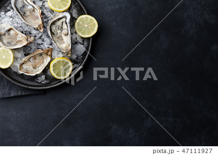Fresh oysters in a plate with ice on black background 47111927