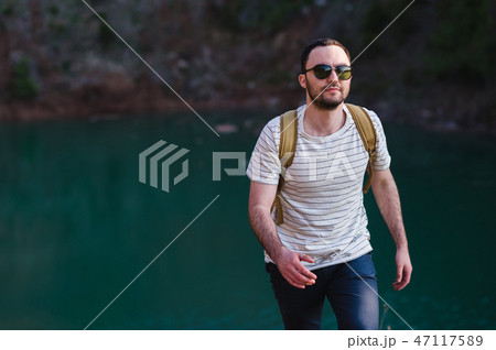 Hiking man portrait with backpack walking in nature. Caucasian man smiling happy with forest in 47117589