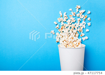 Popcorn poured from white paper cup on blue background. mock-up. 47117754