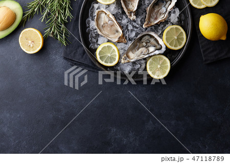 Fresh oysters in a plate with ice on black table Fresh oysters in a plate with ice on black table 47118789