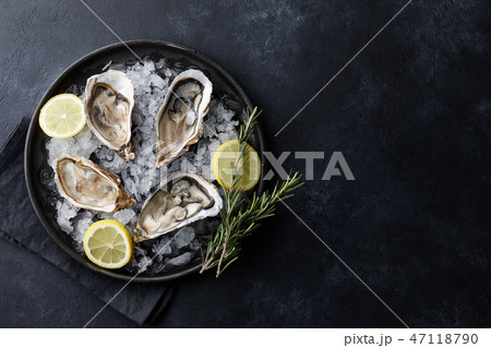 Fresh oysters in a plate with ice on black table Fresh oysters in a plate with ice on black table 47118790