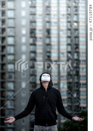 Mystery man in white mask standing in the rain 47119784