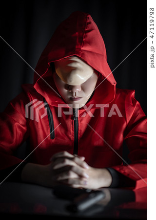 Mystery man in red hoodie sitting in the dark Mystery man in red hoodie sitting in the dark 47119798