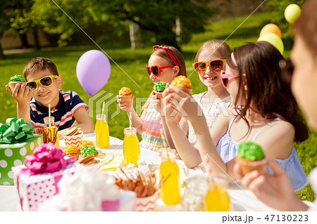 kids eating cupcakes on birthday party in summer 47130223