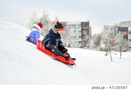 kids sliding on sleds down snow hill in winter kids sliding on sleds down snow hill in winter 47130567