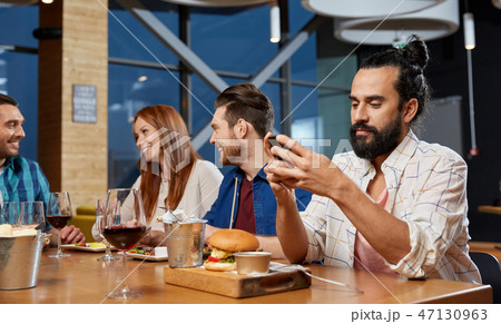 man messaging on smartphone at restaurant man messaging on smartphone at restaurant 47130963