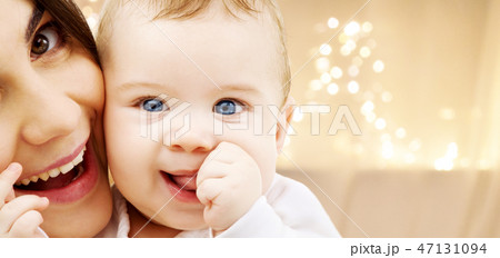 close up of mother with baby over christmas lights close up of mother with baby over christmas lights 47131094
