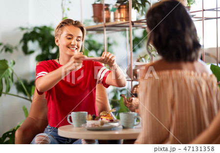 female friends drinking tea with cake at cafe female friends drinking tea with cake at cafe 47131358