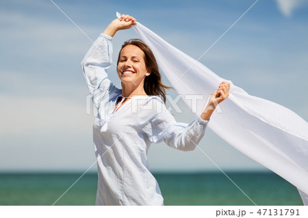happy woman with shawl waving in wind on beach 47131791