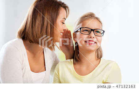 happy mother whispering secret to daughter at home happy mother whispering secret to daughter at home 47132163