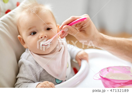 father feeding baby sitting in highchair at home father feeding baby sitting in highchair at home 47132189