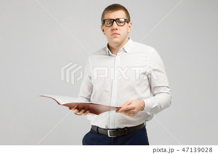 young man in glasses with an open folder in his hands isolated on a light background 47139028