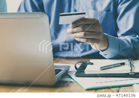 Businessman holding credit card and using laptop. 47140136