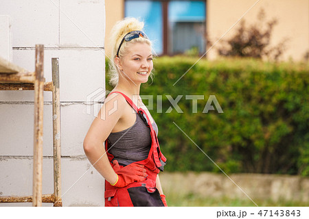 Woman in dungarees working on construction site Woman in dungarees working on construction site 47143843