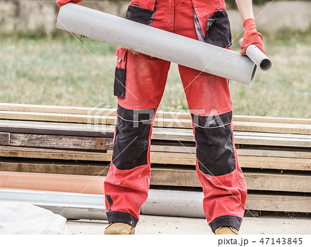 Woman carrying pipes on construction site Woman carrying pipes on construction site 47143845